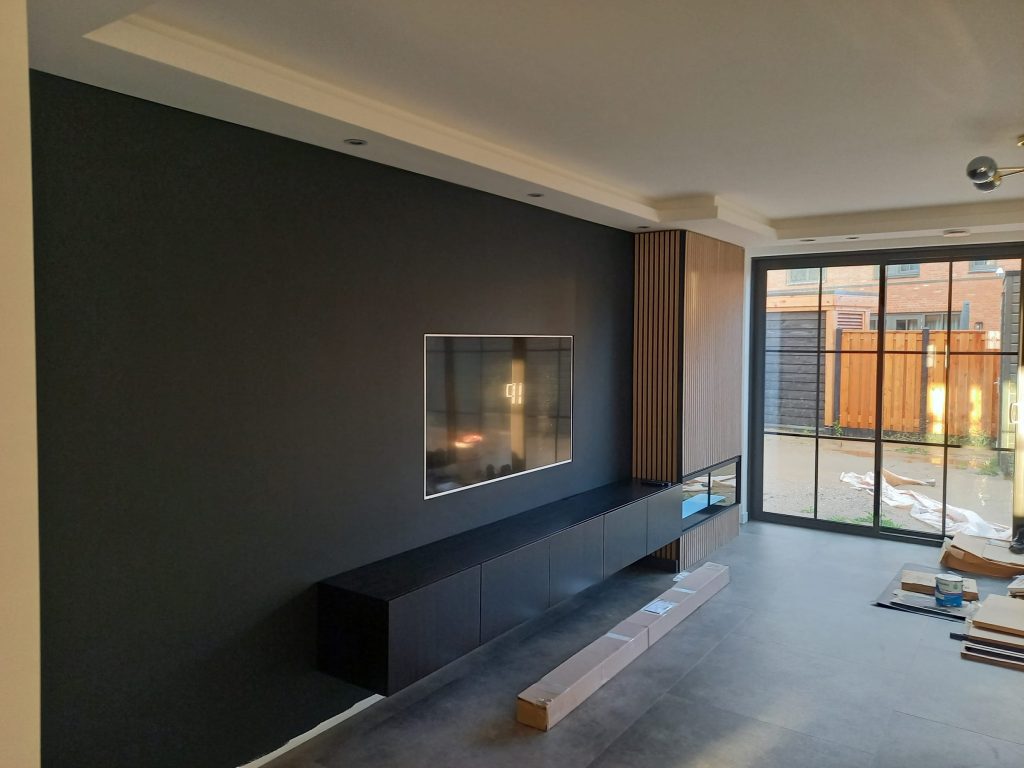 Woonkamer met donkere wand, haard en grote tuindeuren